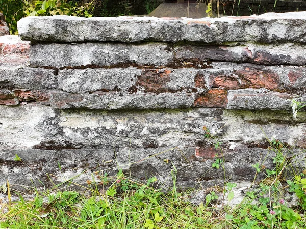 Eski duvar ve çimenler harap olmuş. Eski ev, harabeler, arka plan. Yan görünüm.