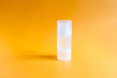 Parlak turuncu arka planda şeffaf bir şişe kayganlaştırıcı jel. Damgalamak ve etiketlemek için şişe.