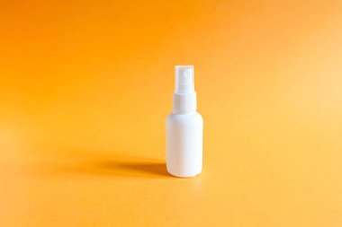 Parlak turuncu bir arka planda markasız beyaz plastik sprey şişesinin maketi. Doğal organik spa kozmetik ürünleri ve sıvı antimikrobik sprey.