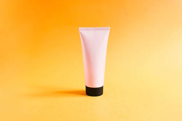 粉色挤压瓶塑料管的模型 黑色的帽子 纹理明亮的橙色背景 用于品牌和标签的瓶子 天然有机温泉化妆品的概念 时尚的影子 — 图库照片
