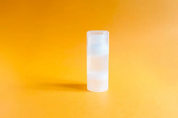 Parlak turuncu arka planda şeffaf bir şişe kayganlaştırıcı jel. Damgalamak ve etiketlemek için şişe.