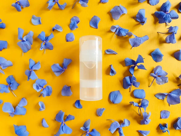 Şeffaf bir şişe kayganlaştırıcı jel ve dokulu turuncu arka planda mavi ortanca çiçekleri. Damgalamak ve etiketlemek için bir şişe. Flatlay, üst görünüm.