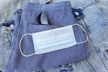 Katlanmış mavi şortlu tıbbi koruyucu yüz maskesi. Modern dünyadaki aksesuarlar. Biyolojik hayat kavramı yeni bir gerçeklikte. Üst görünüm, düz yaşam tarzı.