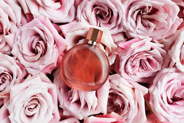 Perfume bottle and light pink roses. Top view, flatlay, mock up. Eau de toilette.