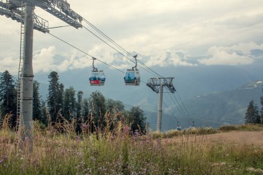 Güneşli bir yaz gününde dağ yamacında turistik bir yerde. Dağ çiçekleri ön planda. Arka planda bulutlar var. Yatay fotoğraf.
