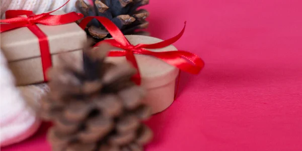 新年横幅。轻便的针织毛衣，圆锥和礼品盒，红色背景上系有红色缎带。侧视图。案文的篇幅. — 图库照片