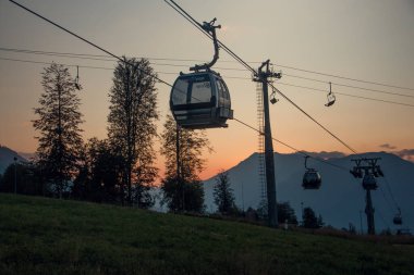 Akşam, gün batımında, füniküler ve dağ zirvelerinin panoramik manzarası. Siluetler. Krasnaya Polyana. Soçi. Yumuşak bir resim. Yatay resim