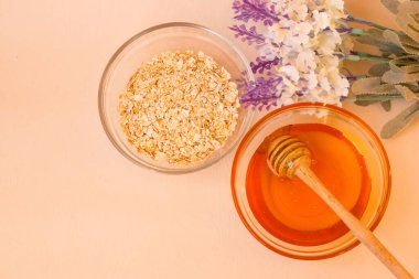 Evde bakım ve kaplıca malzemeleri. Yulaf ezmeli ve sarı ballı cam kavanozlar. Arka planda bir lavanta çiçeği var. Yukarıdan manzara. Güneş ışığı.