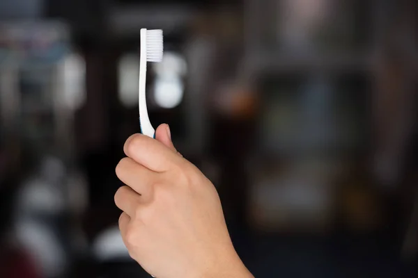 Woman hand holding white toothbrush. — Stock Photo, Image