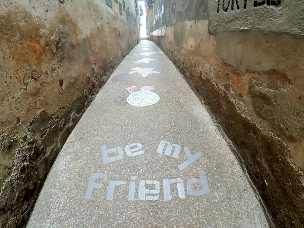 Alley with phrase be my friend and turtles drawn on the ground
