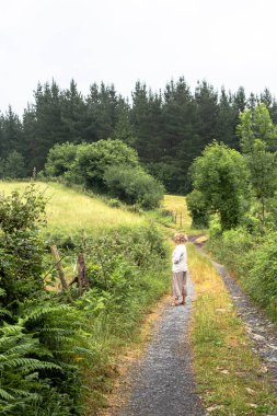 Kadın orman yolunda yürüyor.