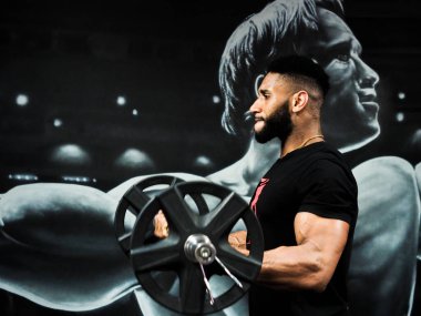 Kaslı adam bisepsi kıvırıyor.