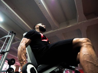 Kaslı adam bisepsi kıvırıyor.