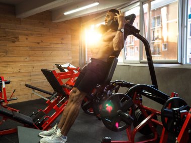 fitness çocuğu hack makinesinde çömeliyor.