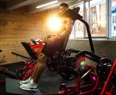 fitness çocuğu hack makinesinde çömeliyor.