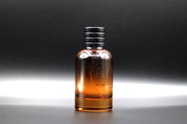 Siyah arka planda etiket ya da çıkartma olmayan kırmızı renkli cam parfüm şişesi.