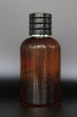 Siyah arka planda etiket ya da çıkartma olmayan kırmızı renkli cam parfüm şişesi.