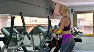 Kadın spor salonunda koşu bandında koşuyor.