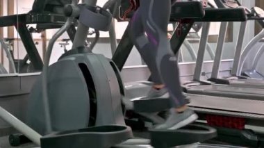 Kadın spor salonunda koşu bandında koşuyor.
