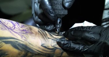 Profesyonel dövme sanatçısı genç bir kızın eline dövme yapıyor.