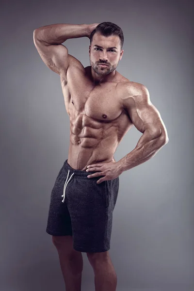 Homem Atlético Forte Mostra Corpo Músculos Abdominais Sobre Fundo Cinza — Fotografia de Stock