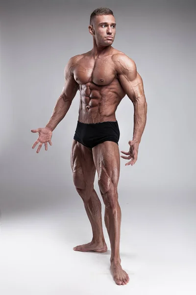 强壮的运动男子显示身体和腹部肌肉的灰色背景 — 图库照片