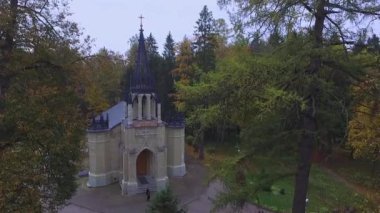 Küçük, güzel bir Gotik kilisenin merkez girişinden uçarak uzaktaki çok katlı şehirli evlere tırman ve manzarayı izle.