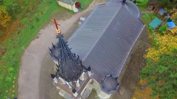 秋の木々に囲まれた清掃に立つ小さなゴシック様式の教会のドームの円形の飛行 — ストック動画