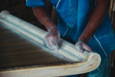 Adamın elleri ahşap kalasları zımparalıyor, bir sürü toz.