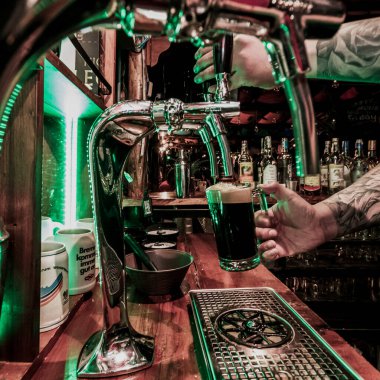 Bardaki bardakları dolduran bira makinesi, gece.