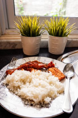 Beyaz pirinç, kızarmış tavuk ve hindistan cevizi, tempeh ve sambal ezmesi de dahil olmak üzere Endonezya usulü yemekler bir mutfakta çatal ve kaşıkla servis edilir. Endonezya geleneksel yemeği