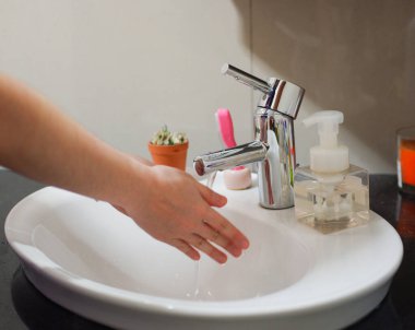 Açık tenli Asyalı kadın lavaboda ellerini duruluyor. Virüs ya da bakteriyel yayılma önleme için hijyen ve temizliği gösterir