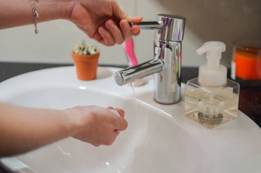 Açık tenli Asyalı kadın banyo lavabosunda köpüklü ellerini sabunla yıkıyor. Virüs ya da bakteriyel yayılma önleme için hijyen ve temizliği gösterir