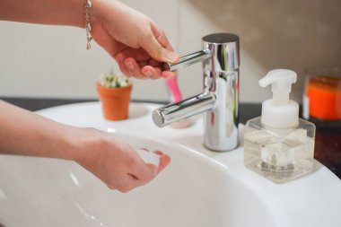 Açık tenli Asyalı kadın banyo lavabosunda köpüklü ellerini sabunla yıkıyor. Virüs ya da bakteriyel yayılma önleme için hijyen ve temizliği gösterir