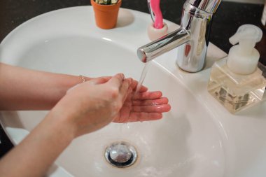 Açık tenli Asyalı kadın banyo lavabosunda köpüklü ellerini sabunla yıkıyor. Virüs ya da bakteriyel yayılma önleme için hijyen ve temizliği gösterir