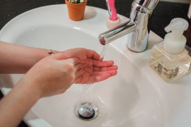 Açık tenli Asyalı kadın banyo lavabosunda köpüklü ellerini sabunla yıkıyor. Virüs ya da bakteriyel yayılma önleme için hijyen ve temizliği gösterir