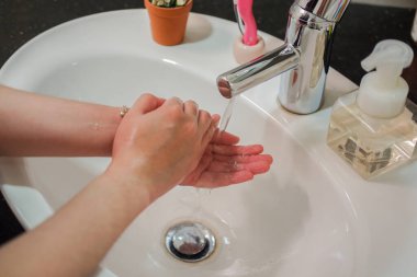 Açık tenli Asyalı kadın banyo lavabosunda köpüklü ellerini sabunla yıkıyor. Virüs ya da bakteriyel yayılma önleme için hijyen ve temizliği gösterir