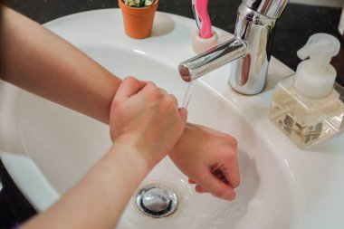 Açık tenli Asyalı kadın banyo lavabosunda köpüklü ellerini sabunla yıkıyor. Virüs ya da bakteriyel yayılma önleme için hijyen ve temizliği gösterir