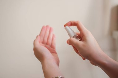 Açık tenli Asyalı bir kadın el dezenfektanı sprey şişesini başka bir ele pompalıyor. Virüs ya da bakteriyel yayılma önleme için hijyen ve temizliği gösterir