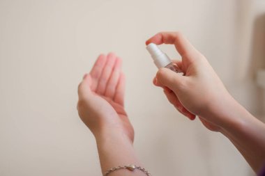 Açık tenli Asyalı bir kadın el dezenfektanı sprey şişesini başka bir ele pompalıyor. Virüs ya da bakteriyel yayılma önleme için hijyen ve temizliği gösterir