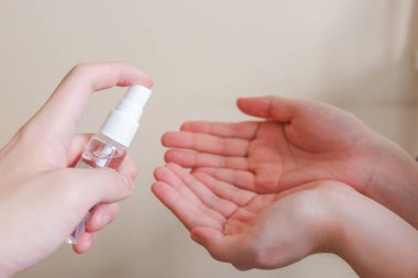 Açık tenli Asyalı bir kadın el dezenfektanı sprey şişesini başka bir ele pompalıyor. Virüs ya da bakteriyel yayılma önleme için hijyen ve temizliği gösterir