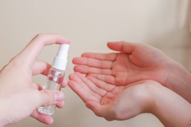 Açık tenli Asyalı bir kadın el dezenfektanı sprey şişesini başka bir ele pompalıyor. Virüs ya da bakteriyel yayılma önleme için hijyen ve temizliği gösterir