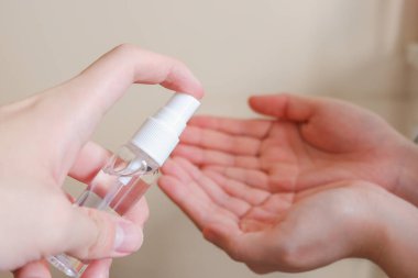 Açık tenli Asyalı bir kadın el dezenfektanı sprey şişesini başka bir ele pompalıyor. Virüs ya da bakteriyel yayılma önleme için hijyen ve temizliği gösterir