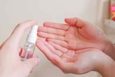 Açık tenli Asyalı bir kadın el dezenfektanı sprey şişesini başka bir ele pompalıyor. Virüs ya da bakteriyel yayılma önleme için hijyen ve temizliği gösterir