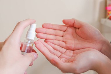 Açık tenli Asyalı bir kadın el dezenfektanı sprey şişesini başka bir ele pompalıyor. Virüs ya da bakteriyel yayılma önleme için hijyen ve temizliği gösterir