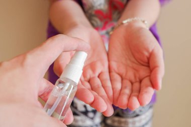 Açık tenli Asyalı bir kadın el dezenfektanı sprey şişesini başka bir ele pompalıyor. Virüs ya da bakteriyel yayılma önleme için hijyen ve temizliği gösterir