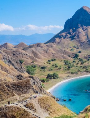 Padar Adası 'nın tepesinden manzara. Turistler Savanna tepesinde eğleniyor ve fotoğraf çekiyorlar..