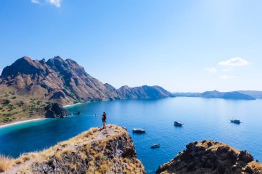 14 Haziran 2018 - Labuan Bajo, Komodo Ulusal Parkı, Endonezya: Padar Adası manzarasının tadını çıkaran ve fotoğraf çeken bir çift. Arka planda tekneler park ediyor.