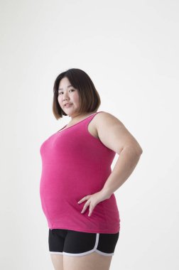 Genç şişman Asyalı kadın ellerini beline koyup kameraya gülümsüyor.