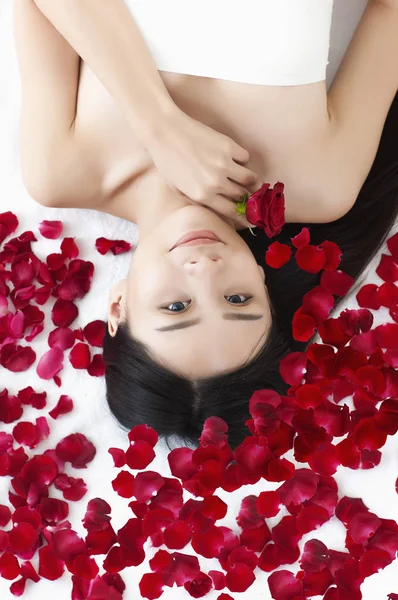 Genç Asyalı Kadın Güllerle Yatakta Uzanıyor Kameraya Gülümsüyor — Stok fotoğraf